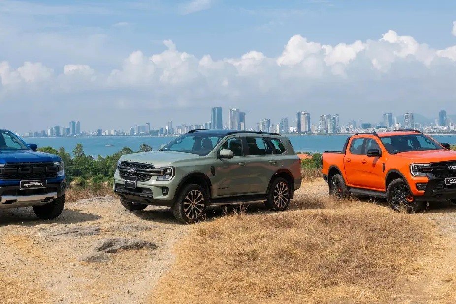 Ranger Raptor màu xanh, Everest màu xanh rêu và Ranger màu cam đỗ trên đồi nhìn ra thành phố ven biển